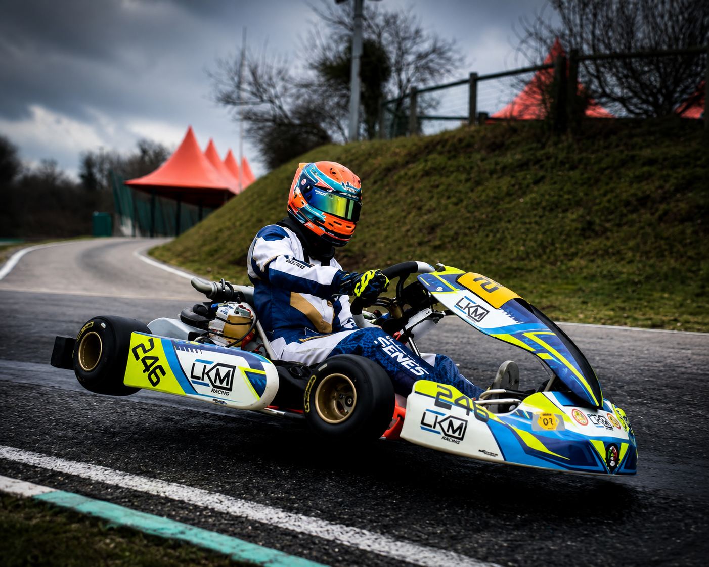 Kart LKM Racing n°246 en pleine action, pilote au casque orange dans un virage